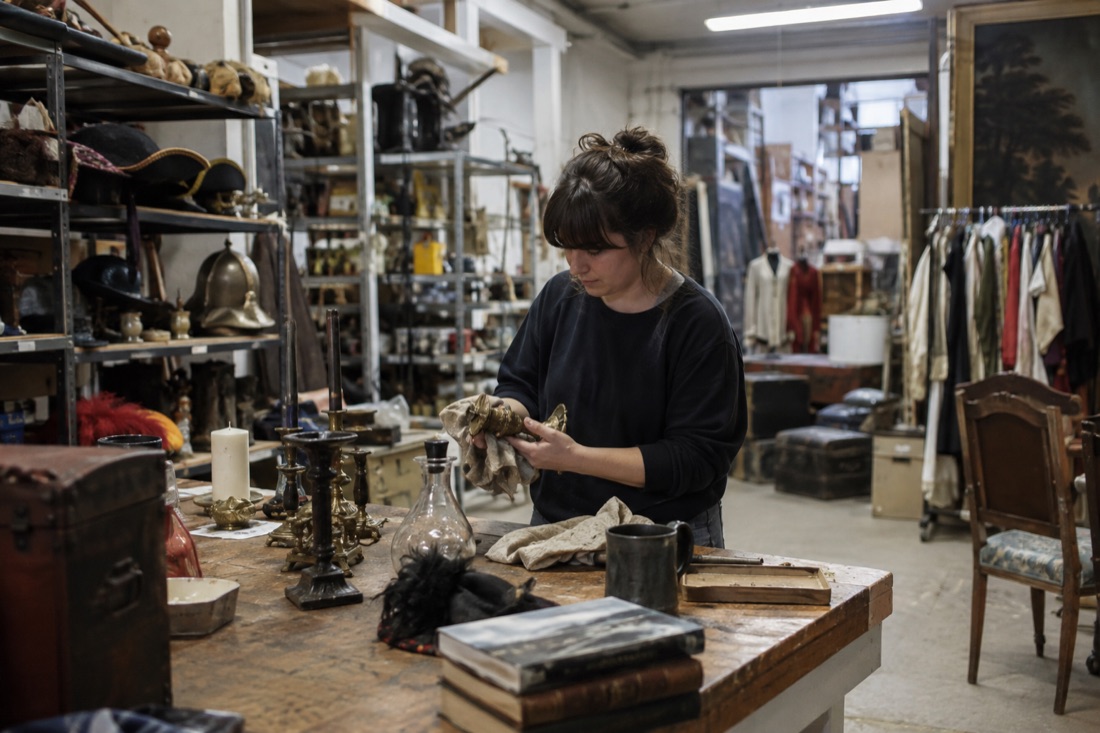 A theatre worker sorts objects in a prop workshop